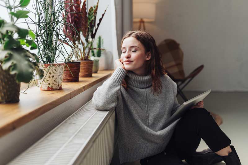 Young woman relaxed at heater with tablet in hand